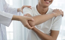 Female physiotherapists provide assistance to male patients with elbow injuries examine patients in rehabilitation centers. Rehabilitation physiotherapy concept.
