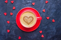 Cup of coffee with heart shape on dark blue background for Valentine's Day greeting card. Top view. 