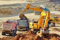 Excavation and loading onto dump trucks with excavators. The work of construction equipment in the production of earthworks
