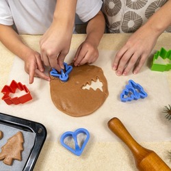 Mom and little daughter with cookie cutters make cookies from dough in the home kitchen. Family and cooking concept
