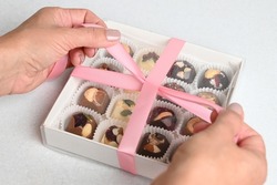 Closeup of a chocolate box present being wrapped. Woman packing home made candy in a gift box. 