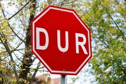 Red stop traffic sign written in Turkish. DUR symbol is a traffic regulator. Sign to stop cars.