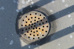 Round storm drain grate with drilled holes in striped shade 