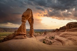 Sunset with stormy skies approaching in Utah, Arches National Park during summertime at Delicate Arch hike with iconic USA landscape. 