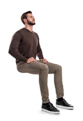 An isolated bearded man in casual wear sits on a white background with hands on his thighs and looks up. Searching for answers. Waiting for help. Thinking of problems.