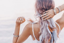 beautiful young boho woman close up with pink feathers and accessories at sunset
