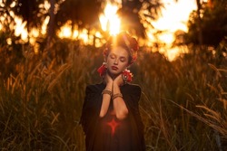 beautiful young fashionable woman posing outdoors on the field at sunset