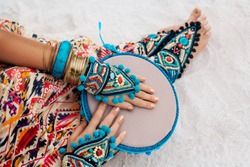 close up of woman hands and legs in ethnic jewelry with drum