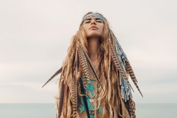 fashion model portrait outdoors. boho style young woman with headdress made of feathers
