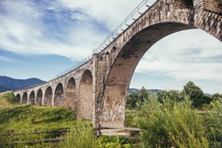 Landscape photography of a large ancient viaduco bridge in the summer mountains on a background of blue sky