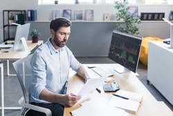 Confident business man stocks broker sitting in front of monitor screen in office analyzing stat of index charts data analyses market trend. Forex trading agency worker agent reviewing profits growth