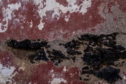 Old plastered volcanic rock stonework wall with worn out red peeling paint, grunge background 