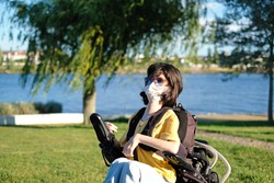 
Disabled woman with muscular dystrophy in an electric wheelchair wearing a white face mask for protection during coronavirus outbreak