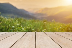 Empty old wooden table in front of blurred view on top of mountains and green field with beautiful sunset background of nature. Can be used for display or montage for show your products.