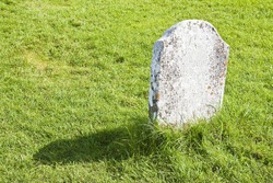 White memorial stone lying on a green grass field - image with copy space