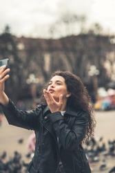 beautiful smiling girl talking on the phone on the street.Sexy girl taking a selfie.
