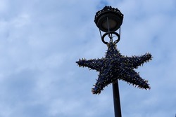 Unlit christmas lights star hanging on a street lamp
