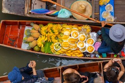Traveler enjoying and take a photo with smartphone on long trail boat at Damnoen Saduak floating market in Ratchaburi near Bangkok, Thailand