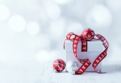 White Christmas Gift with Red Ribbon and Christmas Balls. Copy-space