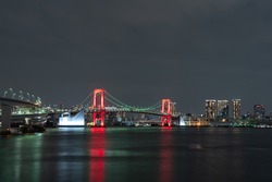 Nightview of Rainbow Bridge illuminated in red as a sign of Tokyo Alert, coronavirus alert for Tokyo area, in Odaiba Japan.
