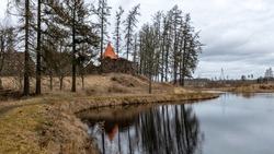 early spring landscape with a view of the castle ruins, the new bright orange roof of the castle tower stands out, Ergeme castle ruins, Valka district, Latvia