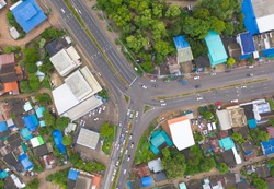 Aerial top view of cars driving with three separate road street in urban city town in Asia, Bangkok, Thailand. Village house buildings with intersection or junction. Traffic.