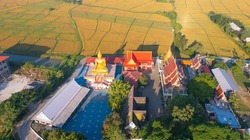 Aerial top view of temple with fresh paddy rice, green agricultural field in countryside or rural area in Asia. Nature landscape background.