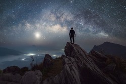 Portrait of man, a tourist, travel at Doi Tung, Chiang Rai, Thailand with mountain hills, the milky way in galaxy with stars at night. Universe space landscape background. People lifestyle.