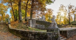 Park stairs with stone statues. Medieval castle in autumn. Autumn landscape of fortress with stone towers surrounded by autumn forest. Cesis castle in Latvia.