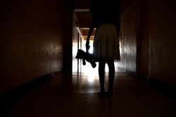 The Ghost of a little girl. Silhouette girls with a toy. A lost childhood. Bringing a child in the hallway. Creepy dark corridor. The light at the end of the tunnel. A deadly backdrop for a Thriller.