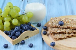 Crispbread with blueberry, grapes and milk on a wooden background
