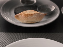 Small French bread  baguette on white plate, wooden table copy space, selective focus, monotone background for wallpaper