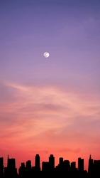 Vertical image, full moon in dramatic vibrant color clouds and sky with silhouette city skyline, twilight, nature wallpaper background