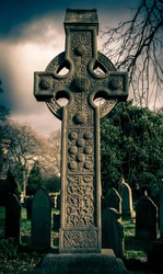 A Victorian old stone weathered cross  dating 1899 marking a grave within a cemetery