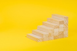 Wooden blocks forming stairway on yellow background. Personal growth, business career path concept. Ladder of success, investment, development .