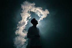 The man smoke an electronic cigarette on the dark background