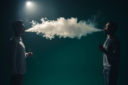 The two man smoke an electrical cigarette on the background of bright light