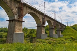Picturesque old railway viaduct, arched stone railway bridge across the river Sluch at bright summer day. Novohrad-Volynskyi city. Ukraine