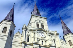 A low, abstract angle of Saint Louis Cathedral on Jackson Square in the New Orleans French Quarter with a dramatic blue sky with white clouds.