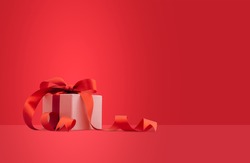 White gift box or present box with red ribbon on red background.
