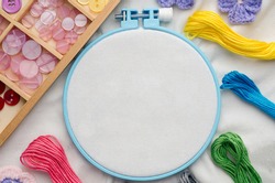 Embroidery hoop with blank fabric, colored sewing threads and various sewing buttons
