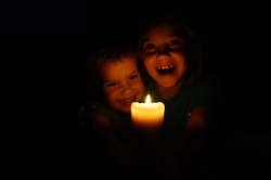 happy laughing kids siblings boy and girl admires a burning wax candle in the evening at home