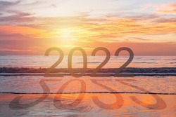 Beautiful sunset with 2022 and shadow on beach. New year concept. Copy space, close up