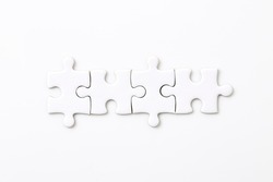 Four white blank puzzle pieces on a white background Merging different elements into a whole
