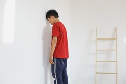 Kid standing in front of the wall because of being punished by the parents, the kid feel sad. 