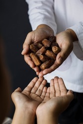 Muslim hands share a fistful of dates. ramadan kareem concept