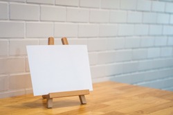 Blank label paper on the wood photo Stand, wood photo holder, white blank paper on frame. mockup. mini sign on wooden table. Layout for menu, sign, label, text. Mini white board. Welcome. Copy Space.