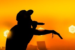 Silhouette of a male singer performing in front of a musical equipment red yellow colours
