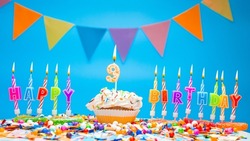 A word made from candle letters happy birthday to a child with the number nine on a beautiful blue background. Copy space Happy birthday greetings for 9 years, lit candles with holiday decorations. 