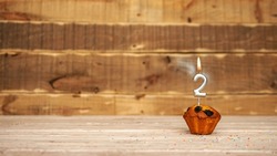 Scenery Festive wooden background happy birthday copy space. Anniversary background with number of burning candles and muffin. Beautiful brown from vintage boards background before a birthday  2